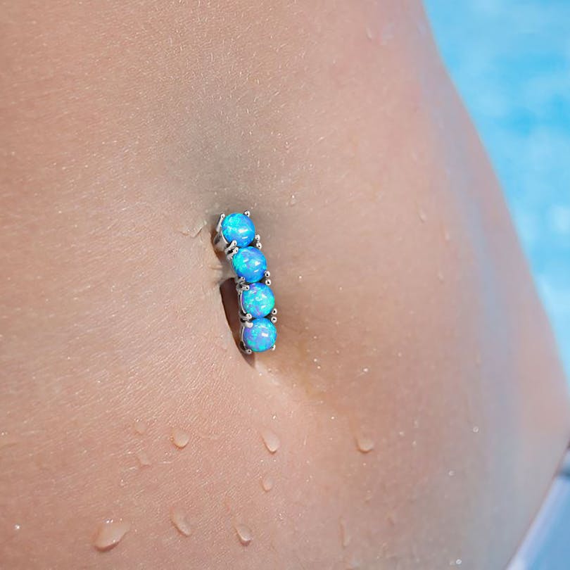 Umgedrehtes Bauchnabelpiercing mit vier Opalsteinen